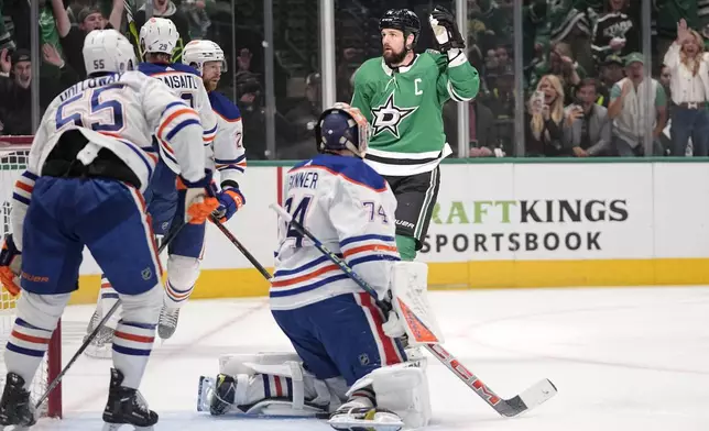 Dallas Stars left wing Jamie Benn (14) celebrates after scoring against Edmonton Oilers goaltender Stuart Skinner (74), as Dylan Holloway (55) and others skate near the goal during the first period in Game 2 of the Western Conference finals in the NHL hockey Stanley Cup playoffs Saturday, May 25, 2024, in Dallas. (AP Photo/Tony Gutierrez)