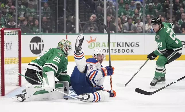Edmonton Oilers left wing Zach Hyman (18) falls over Dallas Stars goaltender Jake Oettinger (29) on a shot attempt as defenseman Thomas Harley (55) watches during the second period in Game 2 of the Western Conference finals in the NHL hockey Stanley Cup playoffs Saturday, May 25, 2024, in Dallas. (AP Photo/Tony Gutierrez)