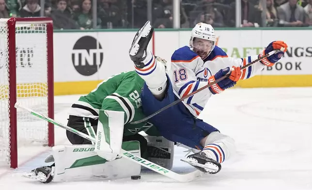 Edmonton Oilers left wing Zach Hyman (18) falls backward over Dallas Stars goaltender Jake Oettinger (29) on a shot-attempt during the second period in Game 2 of the Western Conference finals in the NHL hockey Stanley Cup playoffs Saturday, May 25, 2024, in Dallas. (AP Photo/Tony Gutierrez)