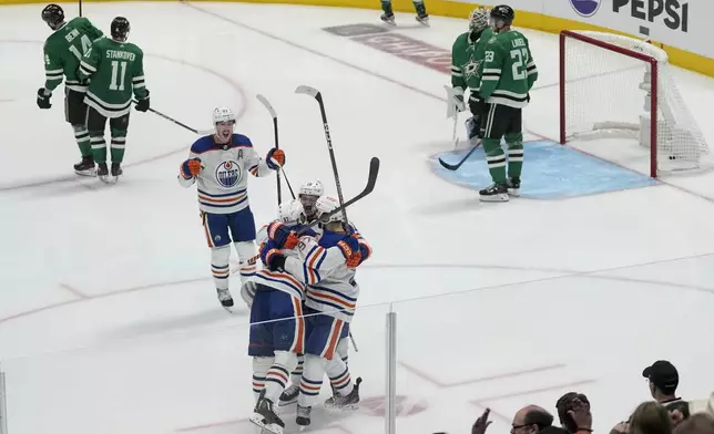Edmonton Oilers players celebrate a game-winning goal by center Connor McDavid, bottom, left, during the second overtime in Game 1 of the NHL hockey Western Conference Stanley Cup playoff finals against the Dallas Stars, Thursday, May 23, 2024, in Dallas. (AP Photo/Tony Gutierrez)