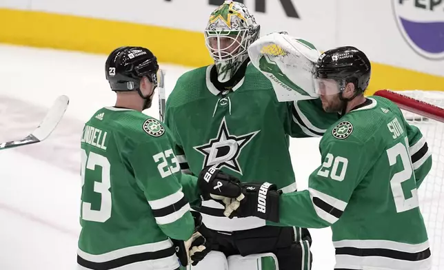 Dallas Stars' Esa Lindell (23), Jake Oettinger, center, and Ryan Suter (20) celebrate after a win over the Edmonton Oilers in Game 2 of the Western Conference finals in the NHL hockey Stanley Cup playoffs Saturday, May 25, 2024, in Dallas. (AP Photo/Tony Gutierrez)