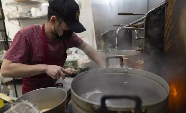 An employee at Chiang Rai Thai Cuisine scrubs a wok on Tuesday, April 30, 2024, in Troutdale, Ore. The family restaurant is run by members of the Iu Mien community. There is a sizeable Iu Mien community in Portland and its suburbs, with a Buddhist temple and Baptist church, active social organization, and businesses and restaurants. (AP Photo/Jenny Kane)