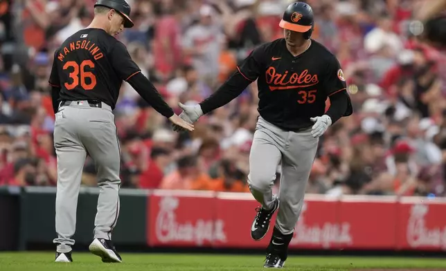 Baltimore Orioles' Adley Rutschman, right, celebrates with third base coach Tony Mansolino, left, as he rounds the bases after hitting a home run in the fifth inning of a baseball game against the Cincinnati Reds, Saturday, May 4, 2024, in Cincinnati. (AP Photo/Carolyn Kaster)
