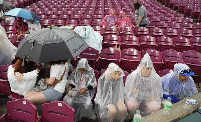 Fans wait in the rain during a rain delay before a baseball game between the Baltimore Orioles and the Cincinnati Reds, Friday, May 3, 2024, in Cincinnati. (AP Photo/Carolyn Kaster)