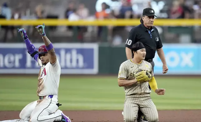 Arizona Diamondbacks' Ketel Marte, left, celebrates his double as San Diego Padres shortstop Ha-Seong Kim, front right, of South Korea, and umpire Phil Cuzzi (10) look for the baseball during the first inning of a baseball game Friday, May 3, 2024, in Phoenix. (AP Photo/Ross D. Franklin)