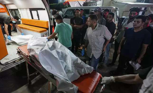 Palestinian medics move dead bodies killed in the Israeli bombardment of Al Zawayda in the central of Gaza Strip to the morgue of Al Aqsa hospital in Deir al Balah, Gaza Strip, early Wednesday, May 22, 2024. (AP Photo/Abdel Kareem Hana)