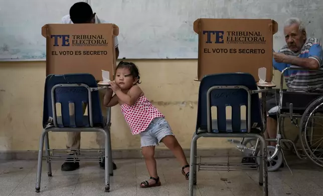 A girl waits for an adult to vote during a general election in Panama City, Sunday, May 5, 2024. (AP Photo/Matias Delacroix)