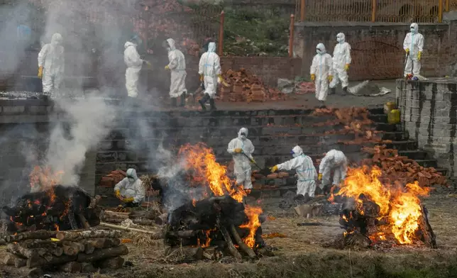 FILE - Men in personal protective suits cremate the bodies of COVID-19 victims as the number of deaths rise near Pashupatinath temple in Kathmandu, Nepal, Wednesday, May 5, 2021. (AP Photo/Niranjan Shrestha, File)