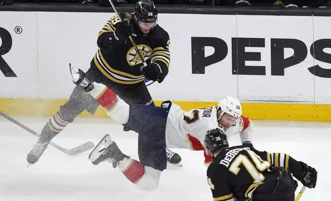 Florida Panthers' Brandon Montour (62) battles Boston Bruins' Morgan Geekie (39) and Jake DeBrusk (74) for the puck during the first period in Game 6 of an NHL hockey Stanley Cup second-round playoff series, Friday, May 17, 2024, in Boston. (AP Photo/Michael Dwyer)