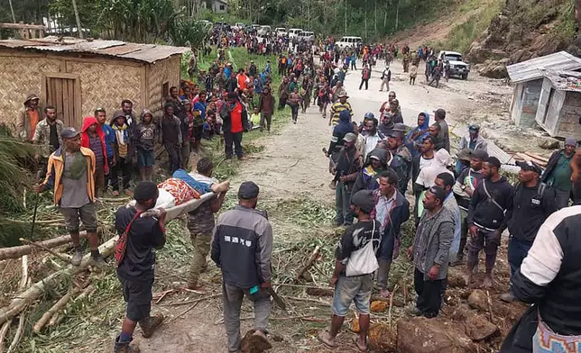 In this photo provided by the International Organization for Migration, an injured person is carried on a stretcher to seek medical assistance after a landslide in Yambali village, Papua New Guinea, Friday, May 24, 2024. More than 100 people are believed to have been killed in the landslide that buried a village and an emergency response is underway, officials in the South Pacific island nation said. The landslide struck Enga province, about 600 kilometers (370 miles) northwest of the capital, Port Moresby, at roughly 3 a.m., Australian Broadcasting Corp. reported. (Benjamin Sipa/International Organization for Migration via AP)