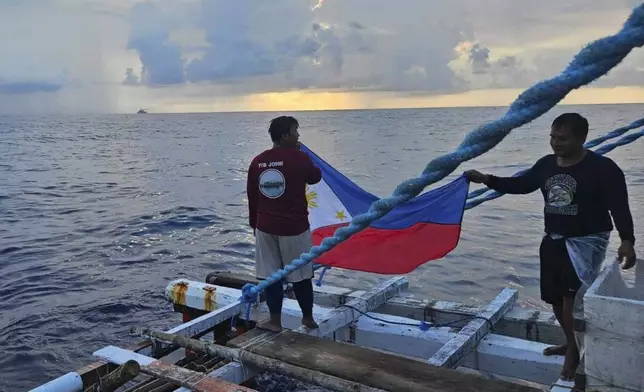 In this photo provided by Atin-Ito/Akbayan Party, fishermen raise a Philippine flag on their boat as activists and volunteers from a nongovernment coalition called Atin Ito, Tagalog for This is Ours, sailed at the South China Sea on Thursday May 16, 2024. About 100 Filipino activists on wooden boats have decided not to sail closer to a fiercely disputed shoal in the South China Sea on Thursday to avoid a confrontation with dozens of Chinese coast guard and suspected militia ships guarding the area. (Atin-Ito/Akbayan Party via AP)