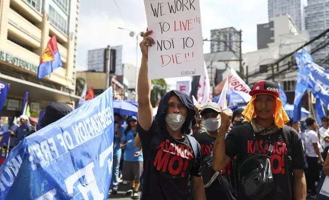 A man carries a poster during a protest to mark International Labor Day near the presidential palace in Manila, Philippines on Wednesday, May 1, 2024. Hundreds of Filipino workers from various labor groups took to the streets to mark Labor Day and demand a wage increase and job security amid soaring food and oil prices. (AP Photo/Basilio Sepe)