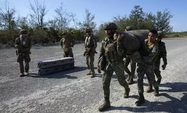Philippine marines carry equipment beside U.S. marines at Paredes Air Station at Pasuquin, Ilocos Norte province during a joint military exercise in northern Philippines on Monday, May 6, 2024. American and Filipino marines held annual combat-readiness exercises called Balikatan, Tagalog for shoulder-to-shoulder, in a show of allied military readiness in the Philippines' northernmost town facing southern Taiwan. (AP Photo/Aaron Favila)