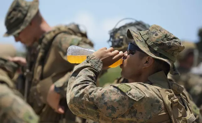 A U.S. marine drinks as he waits under the scorching sun at the airport of the Philippines' northernmost town of Itbayat, Batanes province during a joint military exercise on Monday, May 6, 2024. American and Filipino marines held annual combat-readiness exercises called Balikatan, Tagalog for shoulder-to-shoulder, in a show of allied military readiness in the Philippines' northernmost town facing southern Taiwan. (AP Photo/Aaron Favila)