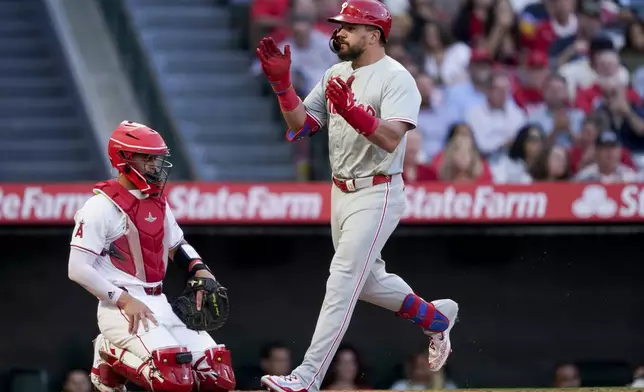 Philadelphia Phillies designated hitter Kyle Schwarber celebrates while crossing home plate next to Los Angeles Angels catcher Logan O'Hoppe after hitting a three-run home run to score Nick Castellanos and Bryson Stott during the second inning of a baseball game, Tuesday, April 30, 2024, in Anaheim, Calif. (AP Photo/Ryan Sun)