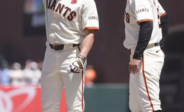 San Francisco Giants' Brett Wisely, left, gestures toward teammates while standing next to first base coach Mark Hallberg, right, after hitting an RBI single during the second inning of a baseball game against the Philadelphia Phillies in San Francisco, Monday, May 27, 2024. (AP Photo/Jeff Chiu)