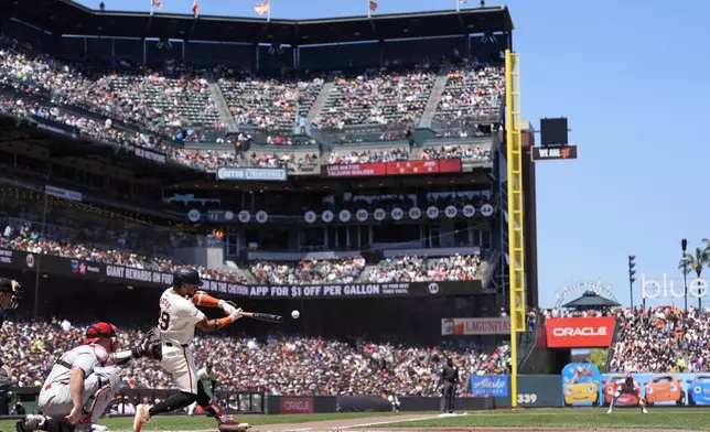 San Francisco Giants' Luis Matos, second from left, hits a single in front of Philadelphia Phillies catcher J.T. Realmuto, left, during the second inning of a baseball game in San Francisco, Monday, May 27, 2024. (AP Photo/Jeff Chiu)