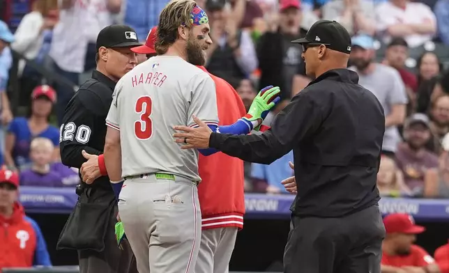 Philadelphia Phillies' Bryce Harper talks to umpire Vic Carapazza, right, after home plate umpire Brian Walsh ejected Harper for arguing a strikeout against Colorado Rockies starting pitcher Ty Blach to end the top of the first inning of a baseball game Friday, May 24, 2024, in Denver. (AP Photo/David Zalubowski)