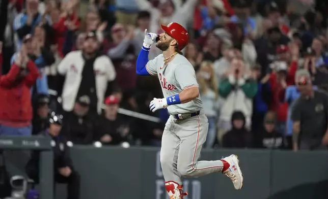 Philadelphia Philliesd' Bryce Harper gestures as he runs the bases after hitting a three-run home run off Colorado Rockies relief pitcher John Curtiss during the ninth inning of a baseball game Saturday, May 25, 2024, in Denver. (AP Photo/David Zalubowski)