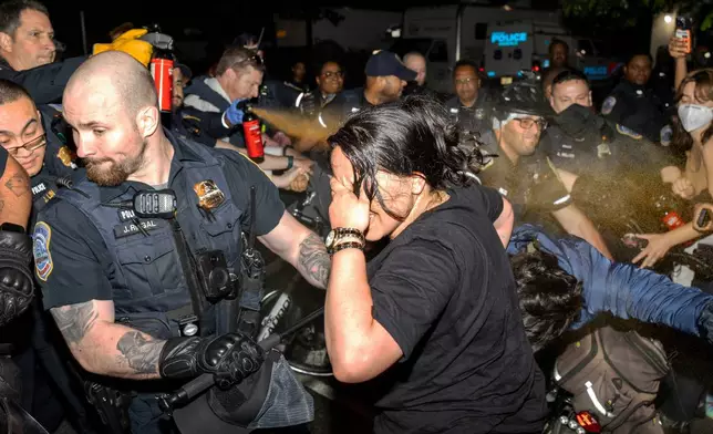 Officers of the Metropolitan Police Department use pepper spray on demonstrators at George Washington University in Washington, early Wednesday, May 8, 2024. Police cleared a pro-Palestinian tent encampment at the university and arrested demonstrators early Wednesday, hours after dozens marched to the home of the school's president. (Sage Russell/GW Hatchet via AP)