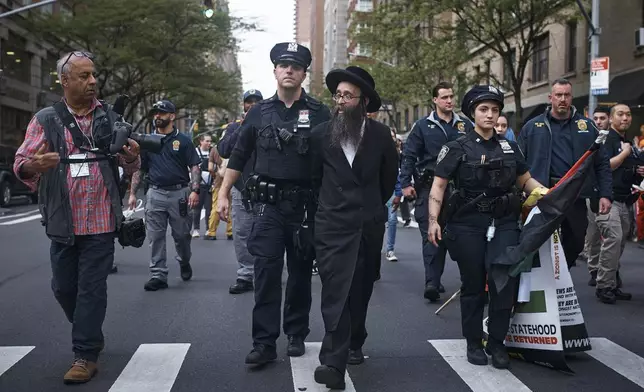 Police escort a pro-Palestinian ultra-Orthodox Jewish demonstrator after detaining him near the Metropolitan Museum of Art where the Met Gala is being held, Monday, May 6, 2024, in New York. (AP Photo/Andres Kudacki)