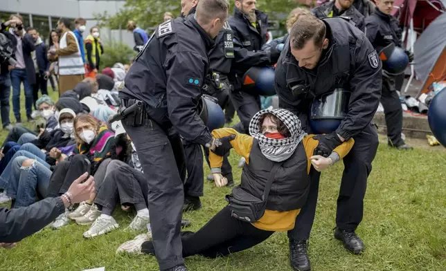 A woman is carried away by police officers during a pro-Palestinians demonstration by the group "Student Coalition Berlin" in the theater courtyard of the 'Freie Universität Berlin' university in Berlin, Germany, Tuesday, May 7, 2024. (AP Photo/Markus Schreiber)