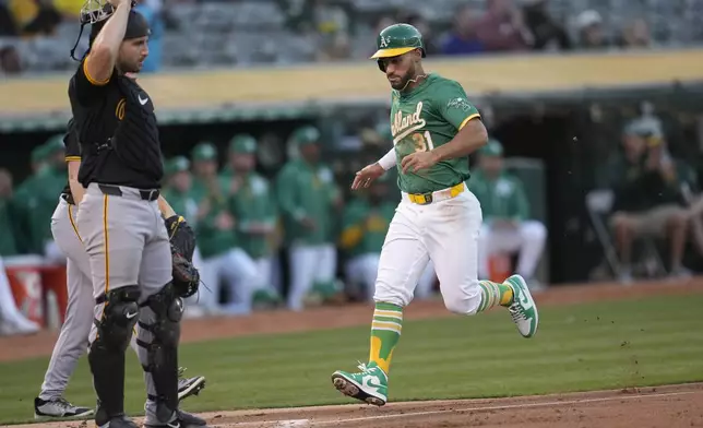 Oakland Athletics' Abraham Toro, right, runs home to score next to Pittsburgh Pirates catcher Joey Bart during the second inning of a baseball game in Oakland, Calif., Tuesday, April 30, 2024. (AP Photo/Jeff Chiu)
