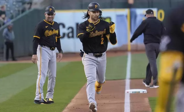 Pittsburgh Pirates' Connor Joe (2) gestures toward teammates past third base coach Mike Rabelo, left, after hitting a home run during the first inning of a baseball game against the Oakland Athletics in Oakland, Calif., Tuesday, April 30, 2024. (AP Photo/Jeff Chiu)
