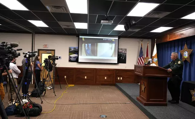 Okaloosa County Sheriff Eric Aden holds a news conference where he shared deputy body cam footage, displayed on screen at center, of the May 3, 2024 shooting of Roger Fortson, a U.S. Navy airman, Thursday, May 9, 2024, in Fort Walton Beach, Fla. Fortson was shot in his apartment after a response to a complaint. (AP Photo/Gerald Herbert)