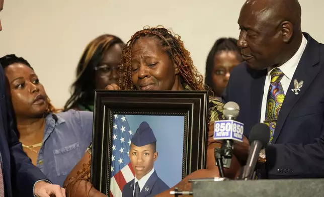 Chantimekki Fortson, mother of Roger Fortson, a U.S. Navy airman, holds a photo of her son during a news conference regarding his death, with Attorney Ben Crump, right, Thursday, May 9, 2024, in Ft. Walton Beach, Fla. Fortson was shot and killed by police in his apartment on May 3, 2024. (AP Photo/Gerald Herbert)