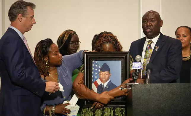 Chantimekki Fortson, mother of Roger Fortson, a U.S. Navy airman, weeps as she holds a photo of her son during a news conference regarding his death, along with family and Attorney Ben Crump, right, and Brian Bar, left, Thursday, May 9, 2024, in Ft. Walton Beach, Fla. Fortson was shot and killed by police in his apartment on May 3, 2024. (AP Photo/Gerald Herbert)