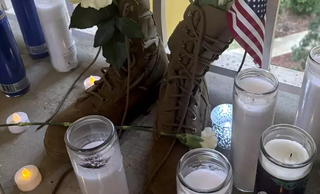 A small shrine is pictured Monday, May 13, 2024, in Fort Walton Beach, Fla. at the door of an apartment where a Florida deputy shot and killed Senior Airman Roger Fortson. The shrine includes a long wooden plank, anchored by two sets of aviator wings and a black marker to leave thoughts, a Stella Artois, and combat boots and an American Flag. As the unit takes a day to grieve and prepare for a funeral Friday, May 17, questions remain about the shooting. (AP Photo)