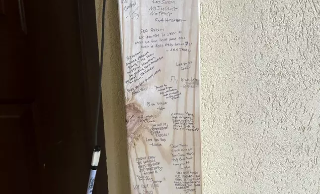 A small shrine is pictured Monday, May 13, 2024, in Fort Walton Beach, Fla. at the door of an apartment where a Florida deputy shot and killed Senior Airman Roger Fortson. The shrine includes a long wooden plank, anchored by two sets of aviator wings and a black marker to leave thoughts, a Stella Artois, and combat boots and an American Flag. As the unit takes a day to grieve and prepare for a funeral Friday, May 17, questions remain about the shooting. (AP Photo)