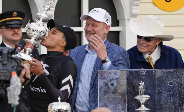 Jaime Torres, left, kisses the Woodlawn Vase, as Seize The Grey part owner, Michael Behrens, center, founder and CEO of MyRacehorse, and trainer D. Wayne Lukas, right, look on after winning the Preakness Stakes horse race at Pimlico Race Course, Saturday, May 18, 2024, in Baltimore. (AP Photo/Julia Nikhinson)