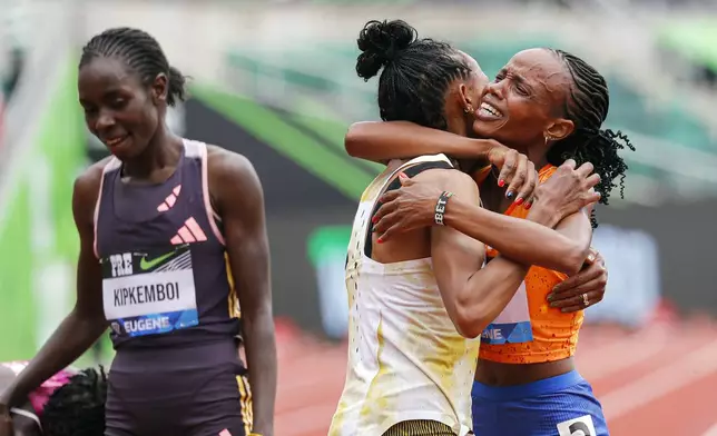 Beatrice Chebet of Kenya, celebrates her world record in the 10,000 with a time of 28:54.14, during the Prefontaine Classic track and field meet Saturday, May 25, 2024, in Eugene, Ore. Gudaf Tsegay, left, of Ethiopia came in second and celebrates with Chebet. (AP Photo/Thomas Boyd)