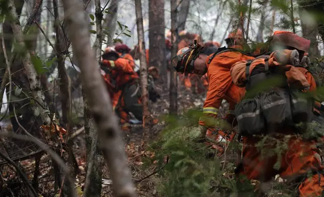 FILE - Inmate firefighters cut down trees along the Highway 29 as wildfires continue to burn Thursday, Oct. 12, 2017, near Calistoga, Calif. California currently has about 1,250 prisoners trained to fight fires and has used them since the 1940s. It pays its "Angels in Orange" $2.90 to $5.12 a day, plus an extra $1 an hour when they work during emergencies. (AP Photo/Jae C. Hong, File)