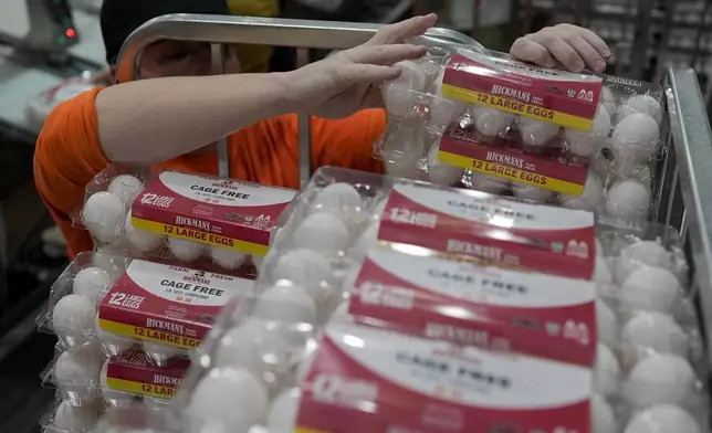 A prison worker, wearing orange, stacks cartons of eggs onto a cart at Hickman's Family Farm egg-packaging operation in Tonopah, Ariz., Thursday, March 14, 2024. (AP Photo/Carolyn Kaster)