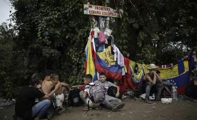 Migrants sit under a sign marking the Panama-Colombia border during their trek across the Darien Gap, Tuesday, May 9, 2023. The image was part of a series by Associated Press photographers Ivan Valencia, Eduardo Verdugo, Felix Marquez, Marco Ugarte Fernando Llano, Eric Gay, Gregory Bull and Christian Chavez that won the 2024 Pulitzer Prize for feature photography. (AP Photo/Ivan Valencia)