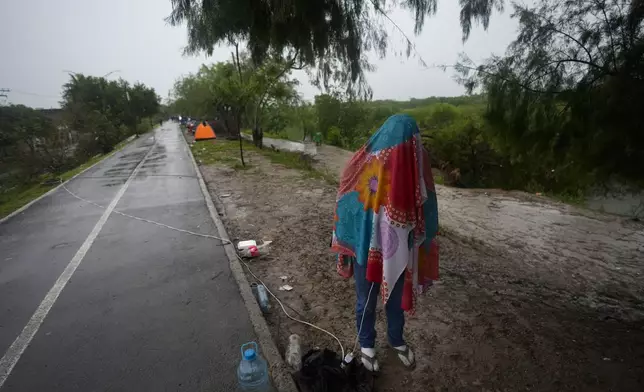 A Venezuelan migrant stands covered in a wrap while texting, on the banks of the Rio Grande in Matamoros, Mexico, Saturday, May 13, 2023. The image was part of a series by Associated Press photographers Ivan Valencia, Eduardo Verdugo, Felix Marquez, Marco Ugarte Fernando Llano, Eric Gay, Gregory Bull and Christian Chavez that won the 2024 Pulitzer Prize for feature photography. (AP Photo/Fernando Llano)