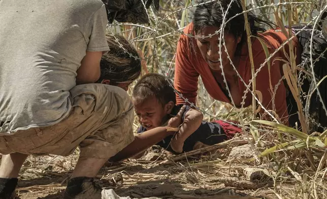Migrants who crossed into the U.S. from Mexico pass under concertina wire along the Rio Grande river, Thursday, Sept. 21, 2023, in Eagle Pass, Texas. The image was part of a series by Associated Press photographers Ivan Valencia, Eduardo Verdugo, Felix Marquez, Marco Ugarte Fernando Llano, Eric Gay, Gregory Bull and Christian Chavez that won the 2024 Pulitzer Prize for feature photography. (AP Photo/Eric Gay)