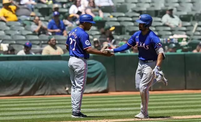 Texas Rangers' Marcus Semien, right, celebrates with third base coach Tony Beasley after hitting a solo home run against the Oakland Athletics during the third inning in the first baseball game of a doubleheader Wednesday, May 8, 2024, in Oakland, Calif. (AP Photo/Godofredo A. Vásquez)