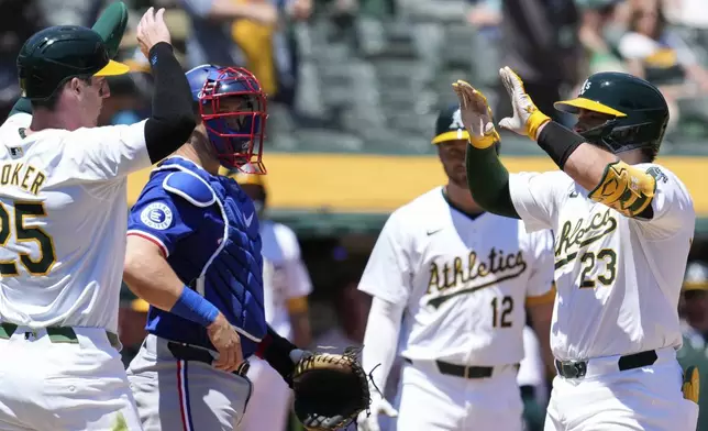 Oakland Athletics' Shea Langeliers, right, celebrates with Brent Rooker, left, after hitting a two-run home run against the Texas Rangers during the second inning in the first baseball game of a doubleheader Wednesday, May 8, 2024, in Oakland, Calif. (AP Photo/Godofredo A. Vásquez)