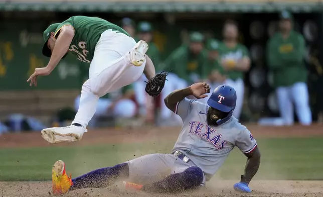 Oakland Athletics pitcher Kyle Muller, left, tags out Texas Rangers' Adolis García at home plate during the eighth inning in the second baseball game of a doubleheader Wednesday, May 8, 2024, in Oakland, Calif. (AP Photo/Godofredo A. Vásquez)