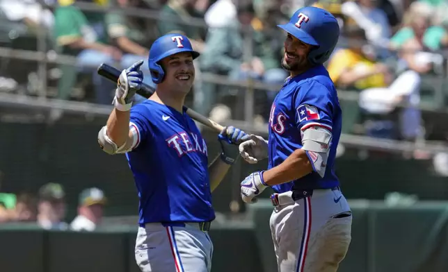Texas Rangers' Marcus Semien, right, celebrates with Nathaniel Lowe after hitting a solo home run against the Oakland Athletics during the third inning in the first baseball game of a doubleheader Wednesday, May 8, 2024, in Oakland, Calif. (AP Photo/Godofredo A. Vásquez)
