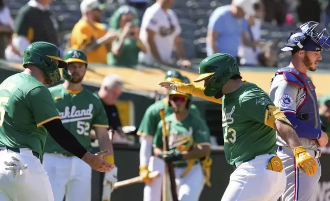 Oakland Athletics' Shea Langeliers (23) celebrates with Seth Brown, left, after hitting a two-run home run against the Texas Rangers during the second inning in the second baseball game of a doubleheader Wednesday, May 8, 2024, in Oakland, Calif. (AP Photo/Godofredo A. Vásquez)