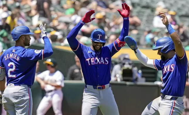 Texas Rangers' Leody Taveras, center, celebrates with Marcus Semien, left, and Ezequiel Duran after hitting a two-run home run against the Oakland Athletics during the fourth inning in the first baseball game of a doubleheader Wednesday, May 8, 2024, in Oakland, Calif. (AP Photo/Godofredo A. Vásquez)