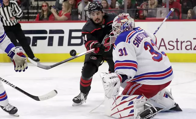 Carolina Hurricanes center Seth Jarvis (24) tries to bat the puck past New York Rangers goaltender Igor Shesterkin (31) during the second period in Game 3 of an NHL hockey Stanley Cup second-round playoff series Thursday, May 9, 2024, in Raleigh, N.C. (AP Photo/Chris Seward)