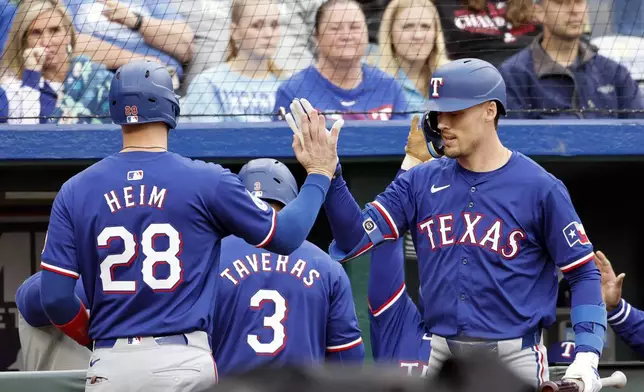 Texas Rangers' Jonah Heim (28) celebrates with Evan Carter, right, after scoring off a Nathaniel Lowe single during the fourth inning of a baseball game against the Kansas City Royals in Kansas City, Mo., Saturday, May 4, 2024. (AP Photo/Colin E. Braley)