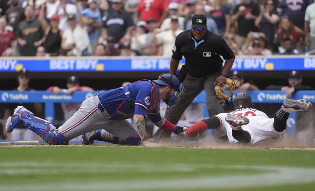 Minnesota Twins' Carlos Santana, right, is tagged out by Texas Rangers catcher Jonah Heim, left, to end the bottom of the seventh inning of a baseball game Saturday, May 25, 2024, in Minneapolis. (AP Photo/Abbie Parr)