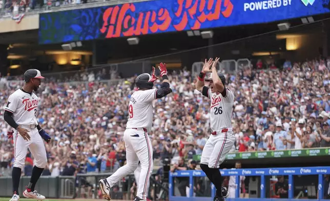 Minnesota Twins' Alex Kirilloff, center, celebrates with Max Kepler (26) after hitting a three-run home run during the eighth inning of a baseball game against the Texas Rangers, Saturday, May 25, 2024, in Minneapolis. (AP Photo/Abbie Parr)